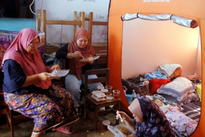 Roziani Arniza Ahmad, 36, (kiri) bersama keluarganya menjamu selera selepas ditempatkan di PPS Sekolah Kebangsaan Sahom. - Foto: Bernama