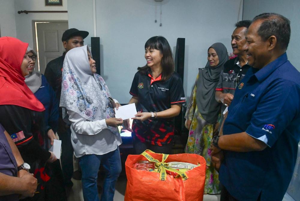 Nie Ching (empat dari kanan) menyampaikan sumbangan kepada warga Kementerian Komunikasi dan Digital yang juga mangsa banjir Rosliza Ghani (dua dari kiri) pada majlis Misi Bantuan Pasca Banjir di Taman Desa Tanjung Damai, Kuala Nerus hari ini. - Foto Bernama