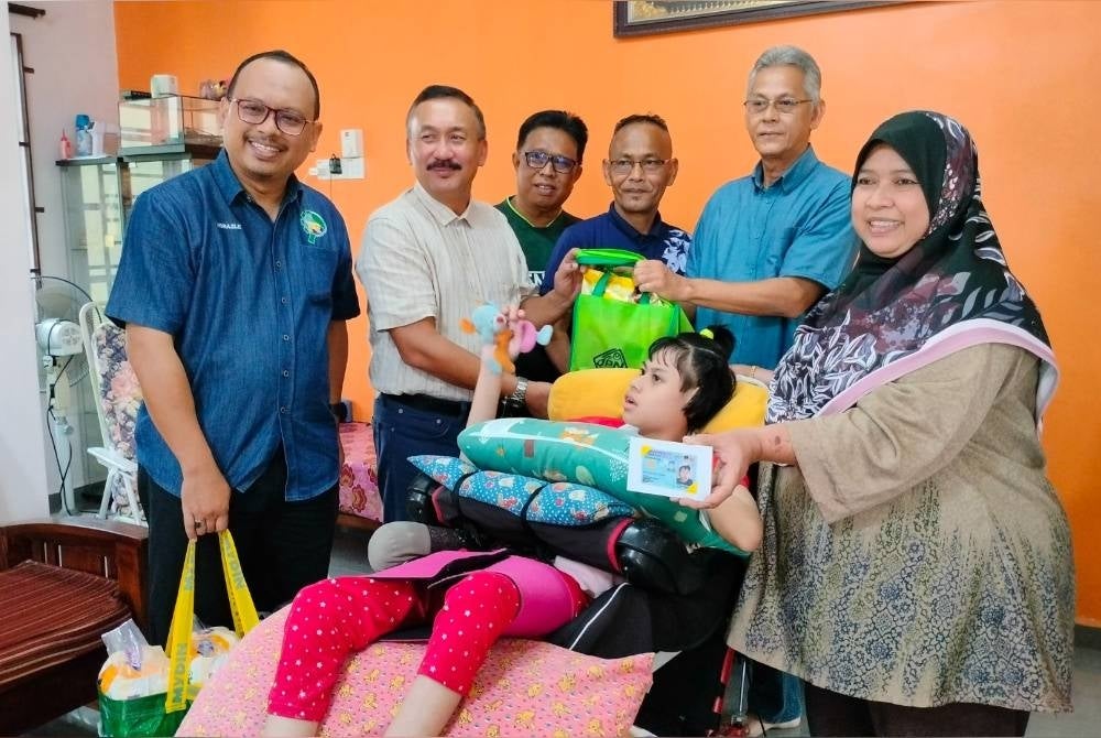 Pengarah JPN Melaka, Norazalee Sulaiman (kiri) mengiringi Ruslin (dua dari kiri) menyampaikan MyKad kepada Rohana (kanan) ketika program MEKAR di Bukit Godek, Semabok pada Sabtu.