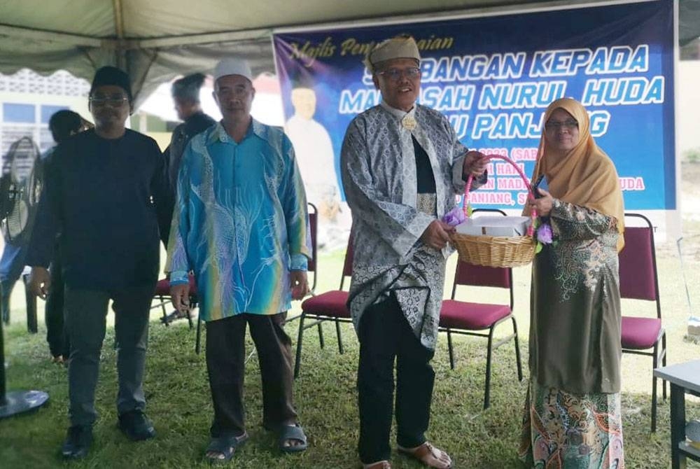 Hamzah (dua dari kanan) menyampaikan sumbangan kepada wakil bagi pembinaan Madrasah Nurul Huda, Rantau Panjang, Selama. Foto: Ihsan pembaca