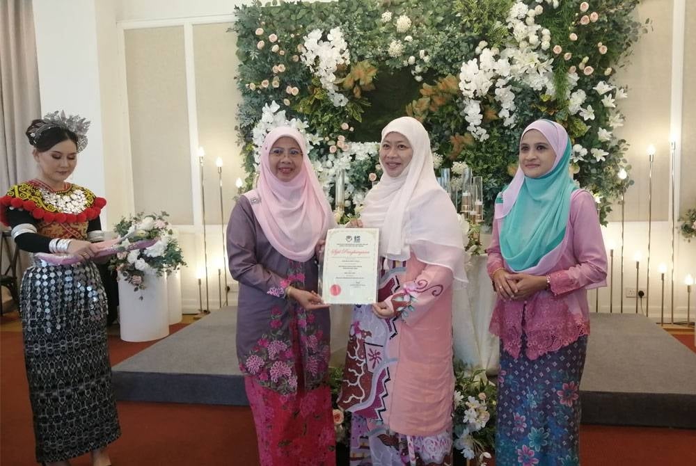 Azuraniza (kiri) menyampaikan anugerah guru besar kepada tenaga pengajar SK Tanjong Malim.