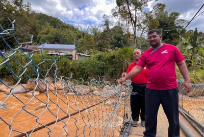 Rian (kanan) bersama Along menunjukkan pagar jambatan besi berusia 15 tahun yang telah rosak dan memerlukan kerja menaik taraf di Kampung Brooke Lama. - Foto Bernama