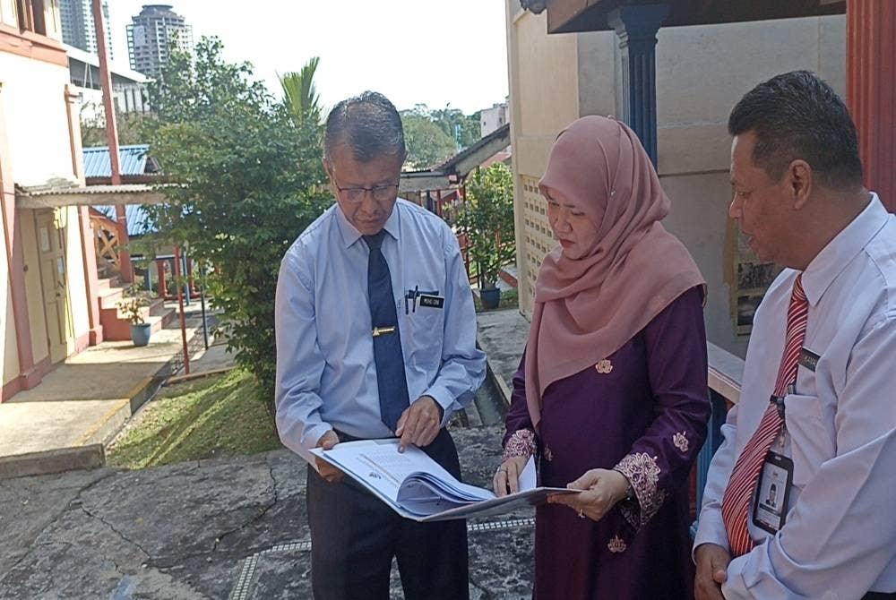 Fadhlina ( tengah) dan Mohd Dini (kiri) berbincang mengenai bangunan Sekolah Kebangsaan (Perempuan), Bandar Tinggi Johor Bahru, pada Isnin.