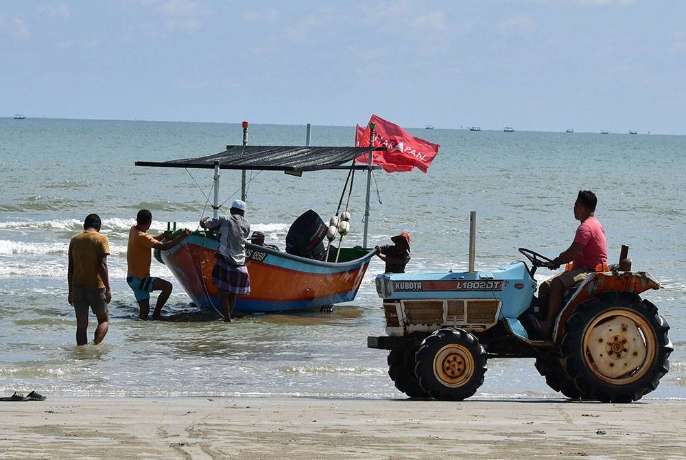 Nelayan menarik bot ke daratan sejurus pulang daripada melakukan aktiviti menangkap hasil laut ketika tinjauan foto Bernama di Pantai Baru hari ini.