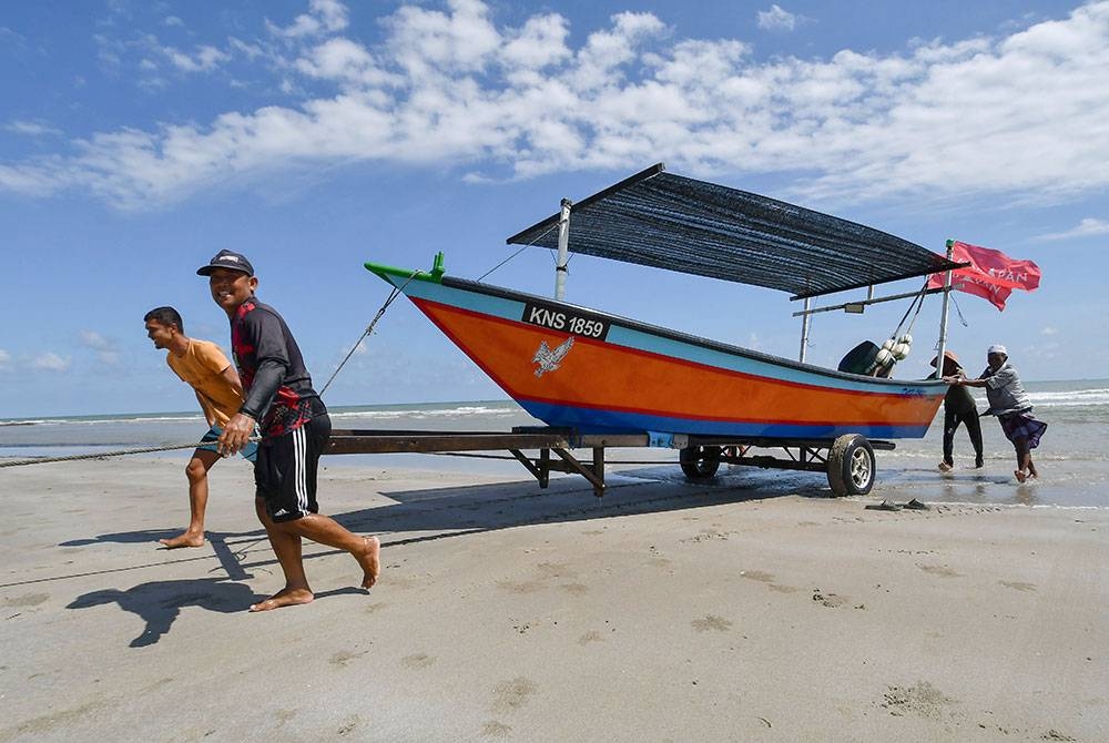 Nelayan menarik bot ke daratan sejurus pulang daripada melakukan aktiviti menangkap hasil laut ketika tinjauan foto Bernama di Pantai Baru hari ini.