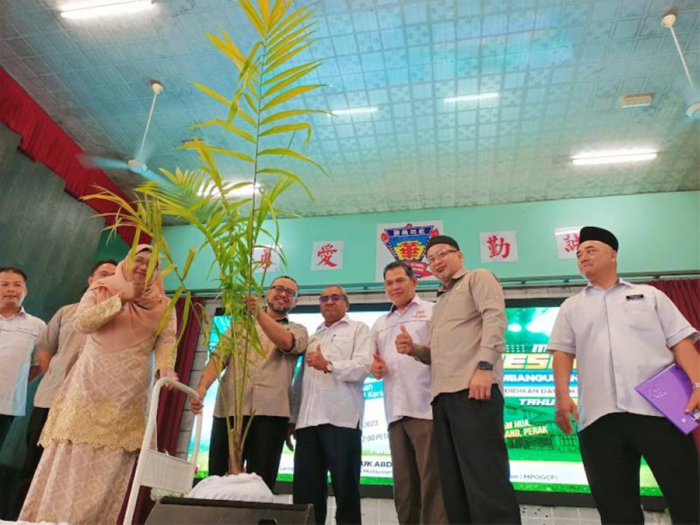 Abdul Rasyid (lima dari kanan) menyempurnakan gimik penyerahan anak pokok kepada wakil sekolah sempena pelancaran Kempen Pemuliharaan Hijau Sekolah-sekolah peringkat PPD Kerian di Dewan SJKC Nam Hua pada Sabtu.