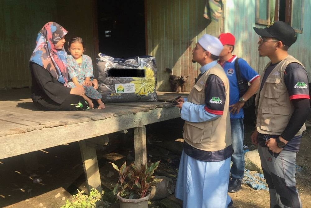 Mohamad Wadi Annuar (dua dari kanan) melawat Suryanie bagi menyampaikan bantuan banjir.