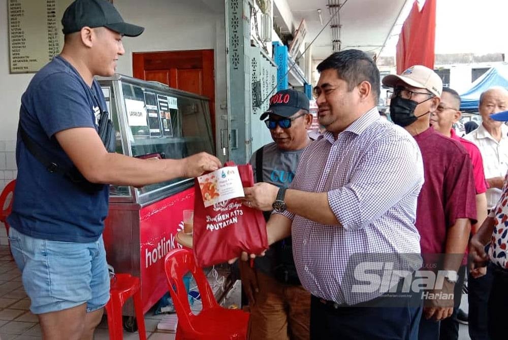 Shahelmey ketika menyampaikan limau mandarin kepada peniaga sekitar Putatan.