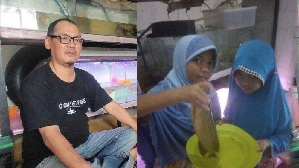 Nizam Naaban (kiri) dan anaknya yang memegang ikan arowana yang digoreng di rumah mereka di Sumatera Utara. - Agensi
