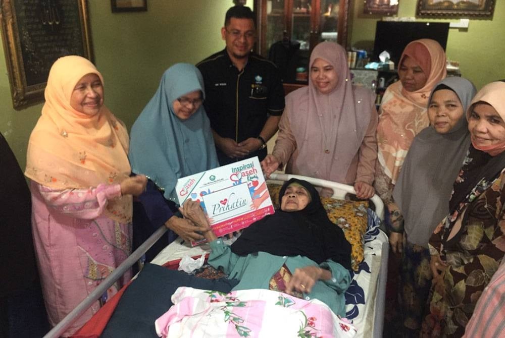 Wan Minah (dua dari kiri) menerima sumbangan yang disampaikan oleh Nik Mohd Nur Ihsan (tiga dari kiri) dan diiringi Dr Hafidzah (kiri).