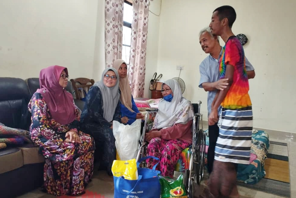 Sabriah (duduk, tengah) melakukan kunjung di rumah keluarga Ramli di Jalan Bukit Palas, Cherating pada Khamis.