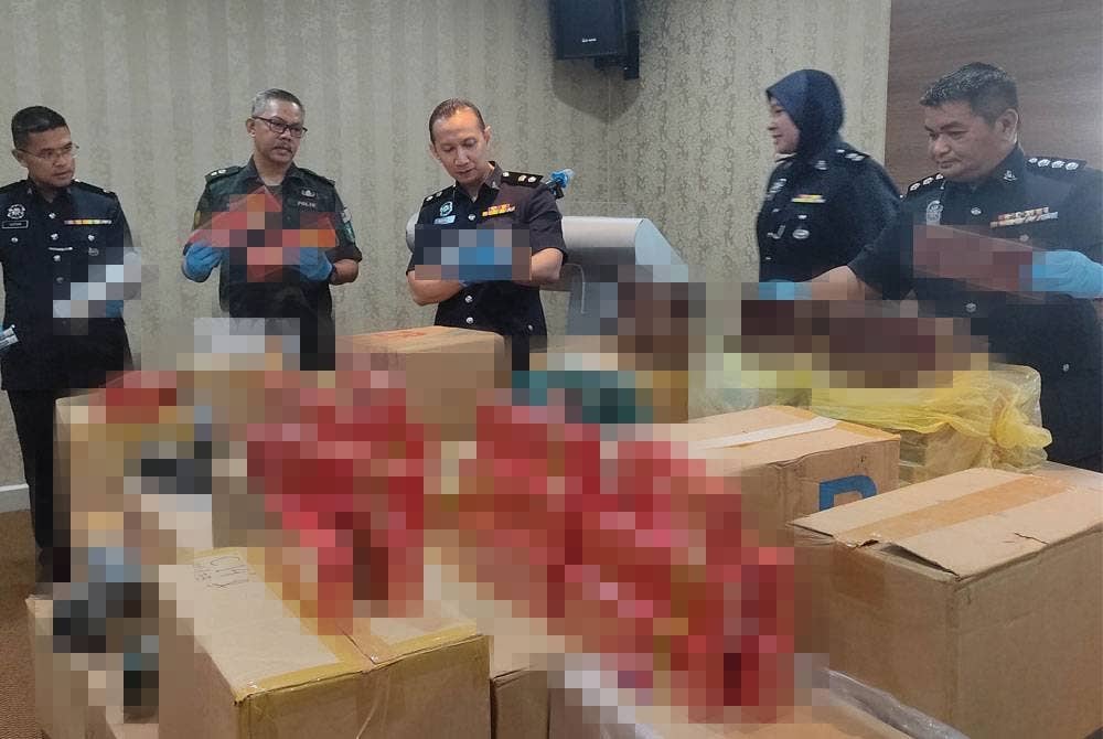 Ahmad Ridhwan (tengah) menunjukkan antara rampasan rokok seludup dalam serbuan di sebuah rumah di Telok Panglima Garang, Banting pada Rabu.