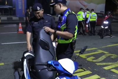 Sarifudin (kiri) memeriksa sebuah motosikal dalam Op Selamat 19 di Jalan Bangsar pada Sabtu.