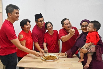 Liang Yeou (tiga dari kiri) bersama keluarganya menggaul hidangan Yee Sang pada malam Tahun Baharu Cina yang diraikan bersama-sama pada Ahad.