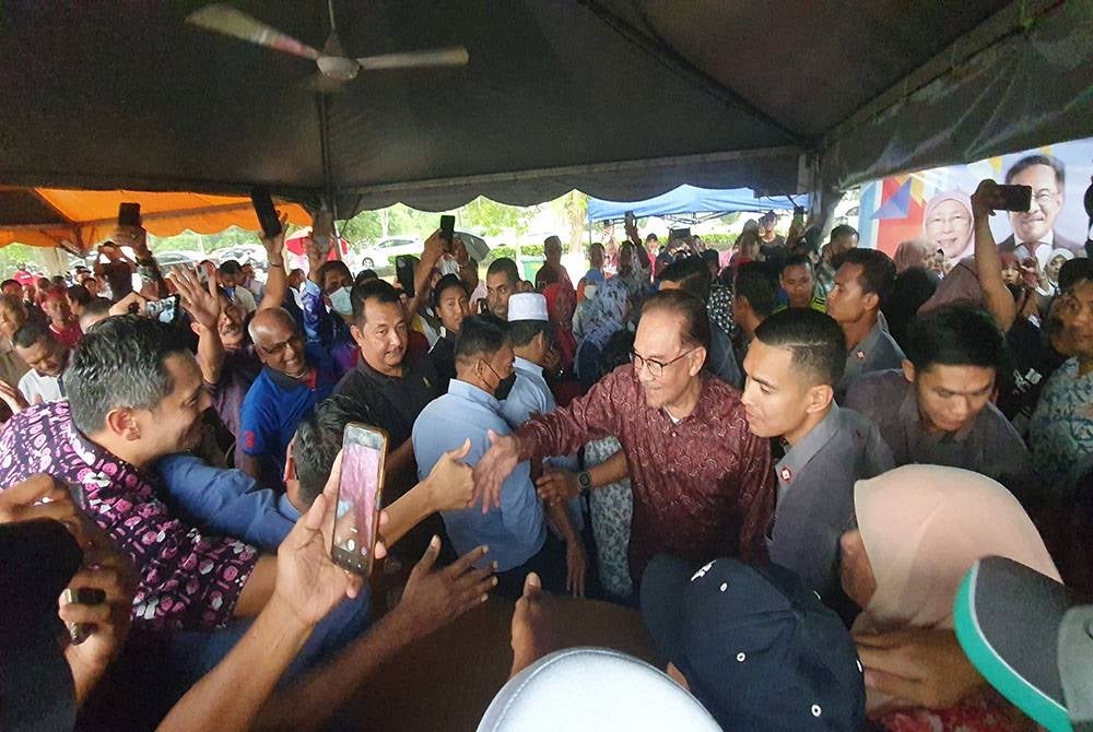 Anwar bersalaman dengan orang ramai pada majlis minum petang bersama rakyat di Lembah Makanan Bandar Perda, pada Isnin.