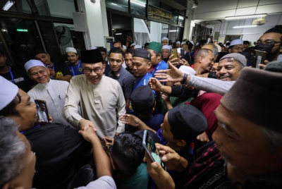 Anwar bersalaman dengan jemaah ketika hadir untuk menunaikan solat Maghrib di Masjid Jamek Cheruk Tok Kun malam ini. - Foto Bernama