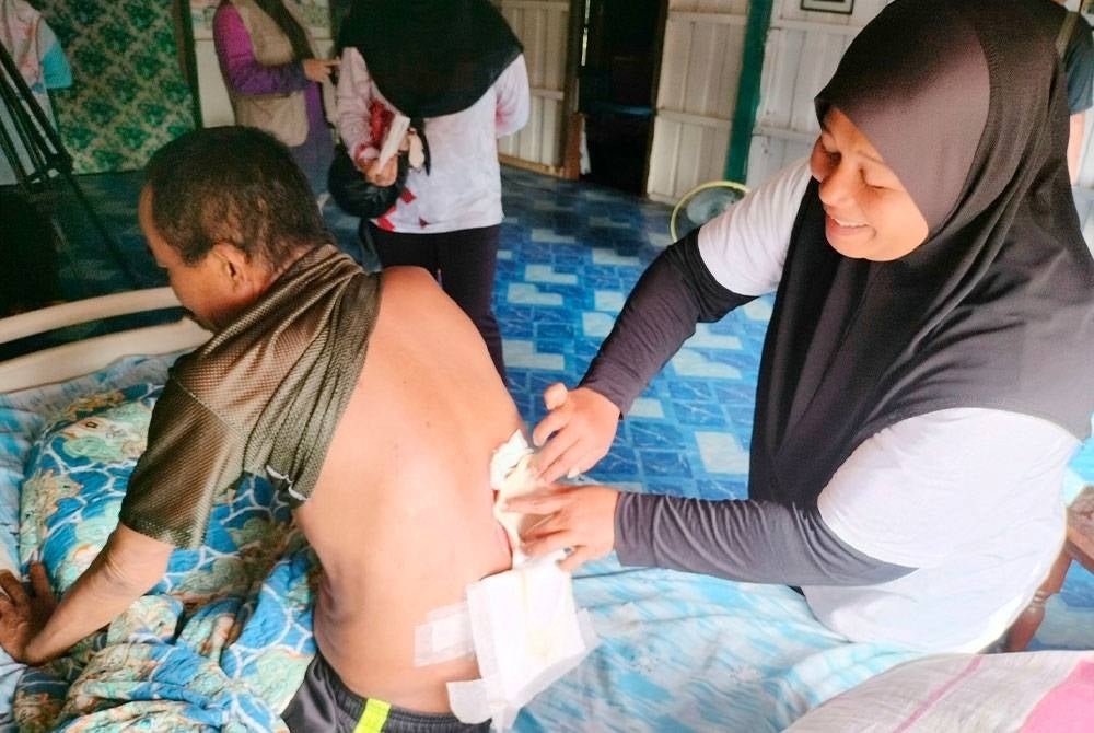 Effa Rizam membantu membalut kudis sebesar tapak tangan pada bahagian belakang suaminya.