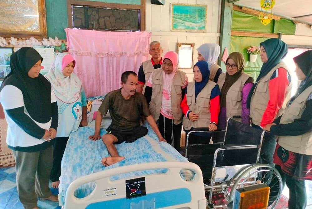 Jamilah (lima dari kanan) menyampaikan kerusi roda, katil khas dan beberapa keperluan lain kepada Maarof ketika mengadakan ziarah di Kampung Cherating Lama pada Selasa.