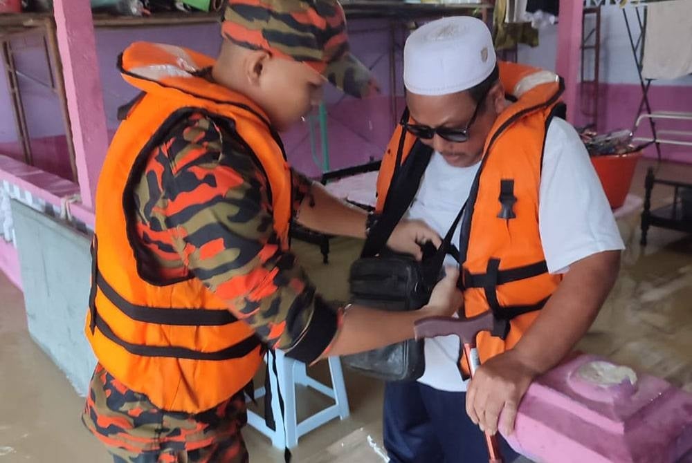 Seorang mangsa banjir dari Perumahan SPKR Yap Tau Sah dibantu anggota bomba untuk dipindahkan ke PPS di SJKC Ping Ming, Kluang, pada Selasa. - Foto ihsan bomba Johor