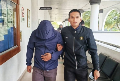 Tertuduh (kiri) di bawa keluar dari mahkamah selepas mendengar proses pendakwaan terhadapnya.