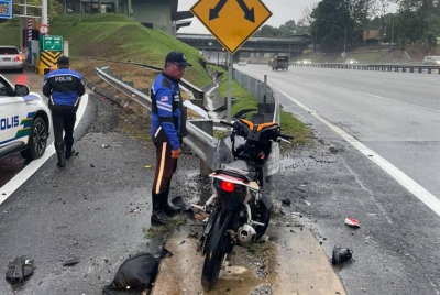 Anggota polis memeriksa motosikal ditunggangi mangsa yang maut selepas terbabas dan merempuh besi pembahagi jalan. - Foto PDRM