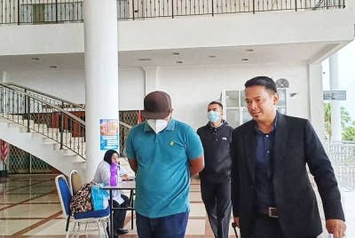 Tertuduh (kiri) diiringi anggota SPRM setelah mendengar pendakwaan terhadapnya di Mahkamah Sesyen, pada Selasa.