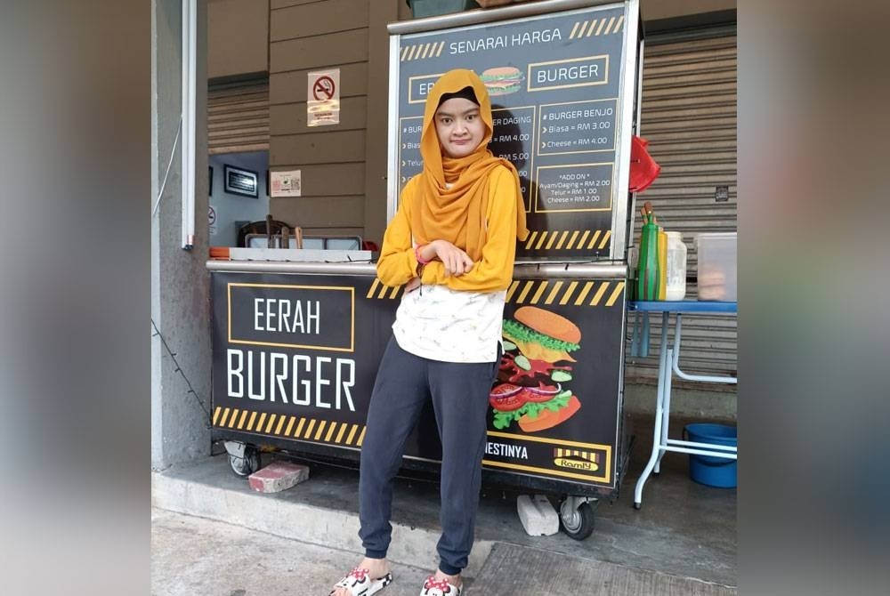 Jaheerah di samping gerai burger yang diusahakan bersama bapa dan abangnya.
