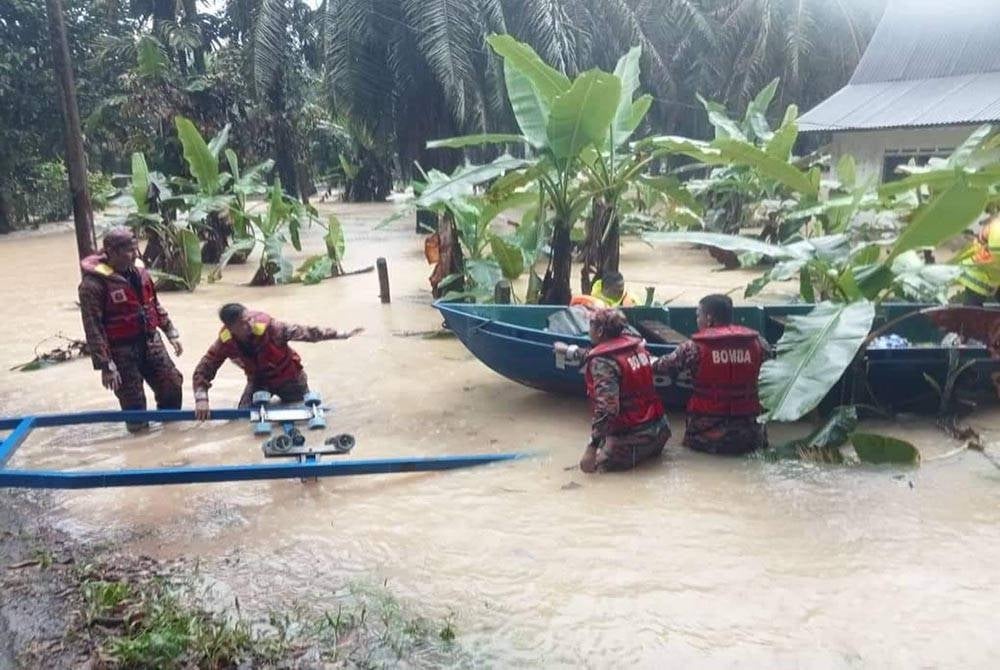 Anggota bomba membantu memindahkan mangsa banjir di Kampung Sekarai Segamat. - Foto Bomba