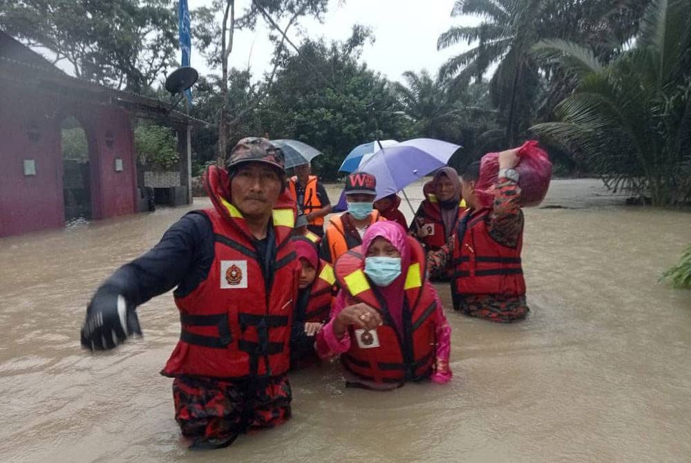 Anggota bomba memindahkan mangsa banjir di Kampung Paya Merah ke PPS di Dewan Serbaguna Kampung Paya Merah, Labis, Segamat, pada Selasa