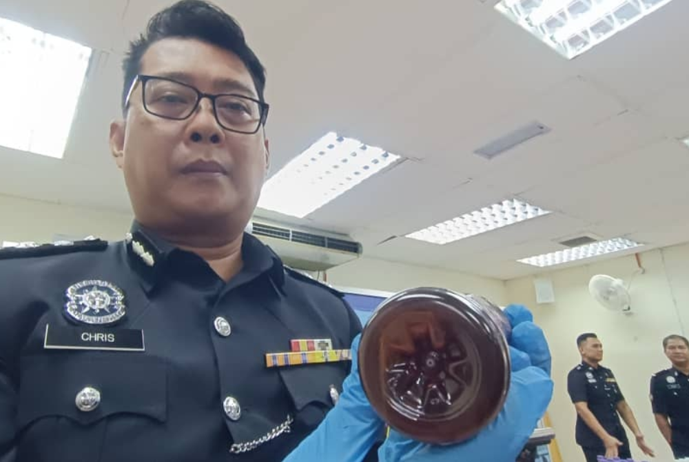 Christopher menunjukkan botol jus yang digunakan untuk menyimpan dadah pada sidang akhbar di IPD Melaka Tengah di Bandar Hilir, Melaka pada Rabu.
