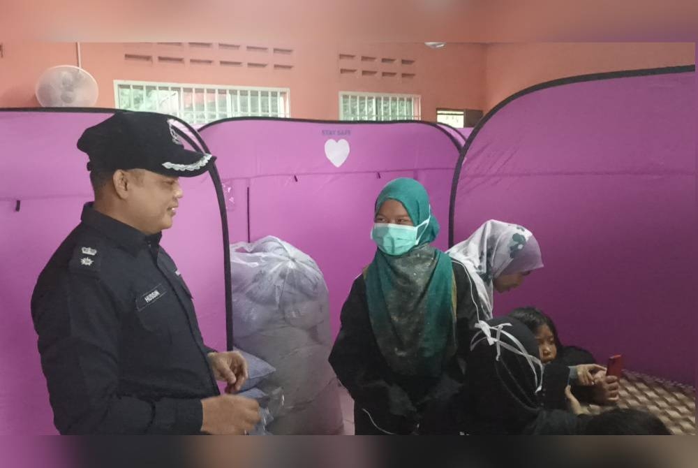 Hussin (kiri) bertanya khabar penduduk yang ditempatkan di PPS Balai Raya Kampung Perpat Sedili pada Rabu.