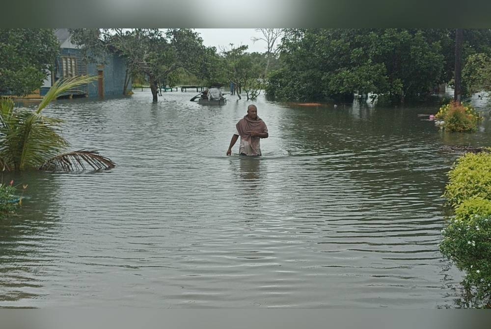 Awang meredah banjir di kawasan halaman rumahnya di Kampung Perpat Sedili.