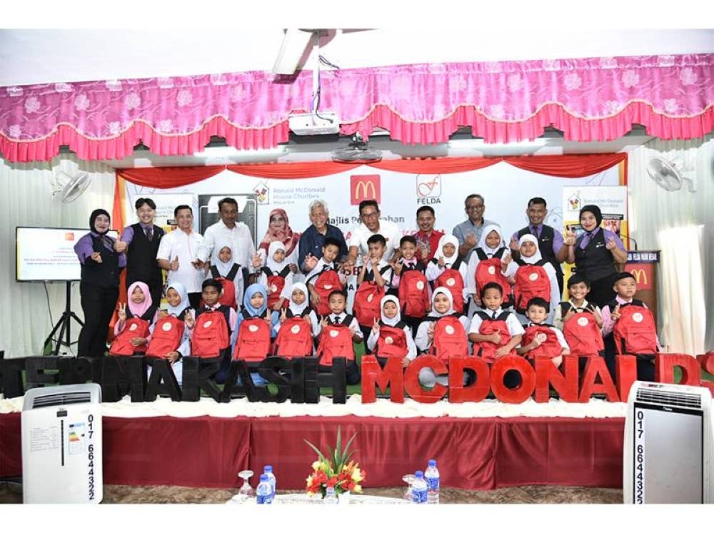 Azmir (belakang, lima dari kanan) dan Idris (belakang, enam dari kanan) bersama para tetamu jemputan serta penerima sumbangan Pek Kembali Ke Sekolah di SK (Felda) Pasir Besar, Gemas.