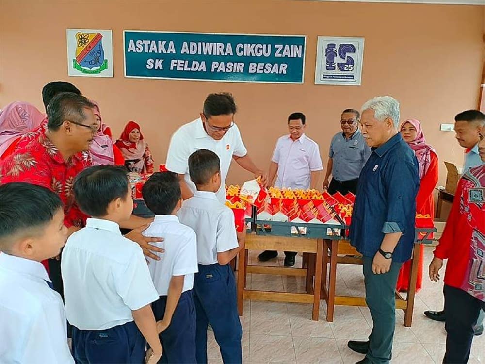 Azmir mengagihkan makanan McDonald’s kepada murid SK (Felda) Pasir Besar, Gemas.