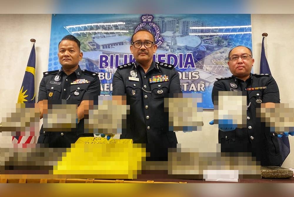 Ahmad Shukri (tengah) menunjukkan ketulan ganja mampat yang dirampas dalam serbuan pada Sabtu lalu.