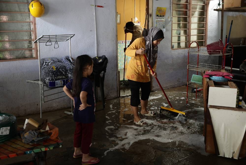 Penduduk Kampung Tenang mencuci kediaman mereka selepas dinaiki air susulan banjir yang melanda beberapa tempat sekitar negeri Johor ketika tinjauan pada Jumaat. - Foto Bernama