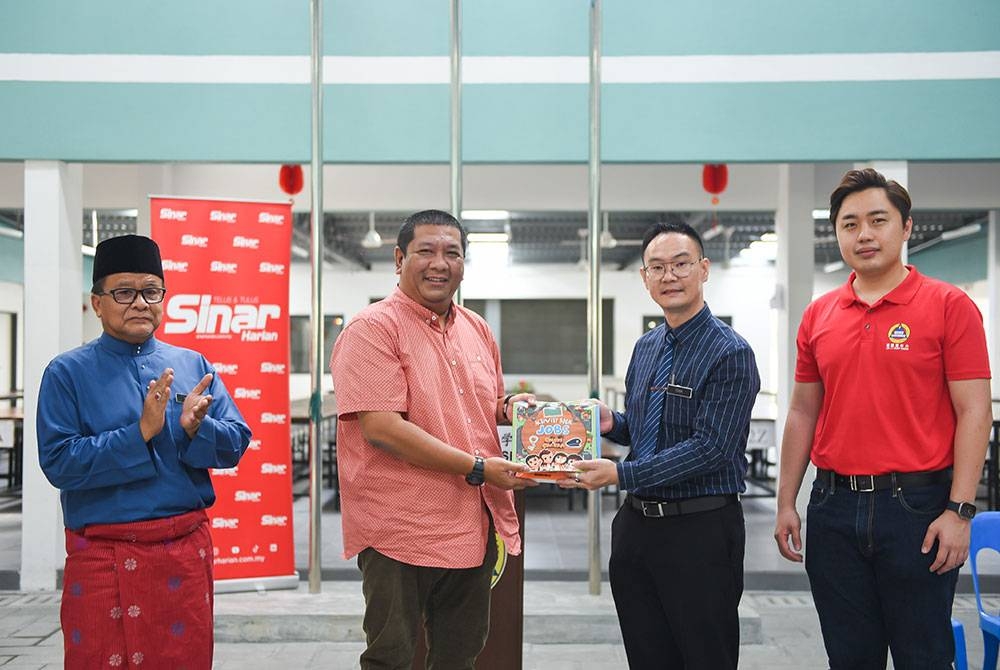 Nik Justin (dua dari kiri) menyampaikan sumbangan buku kepada Khai Hoon pada Jumaat.