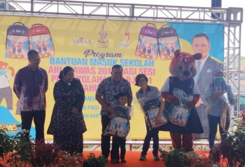 Amirudin (tiga kiri) ketika menyampaikan sumbangan persekolahan Tawas 2016, Tahun Satu bagi sesi persekolahan 2023 di Dewan Rakyat Baru Caves pada Ahad.