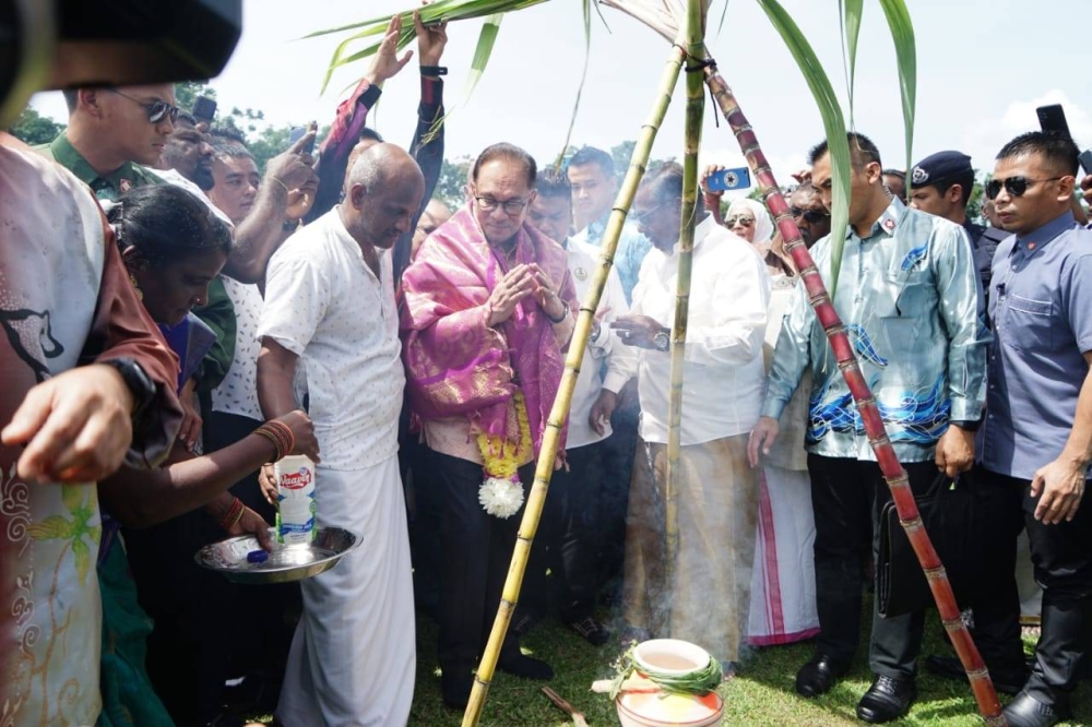 Anwar (tengah) melihat belanga tanah liat yang menyediakan nasi manis pada sambutan Hari Ponggal peringkat Parlimen Tambun di Sekolah Jenis Kebangsaan Tamil Klebang, Chemor pada Ahad.