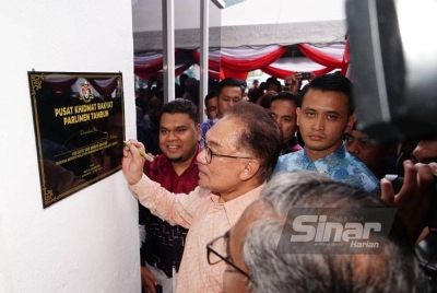 Anwar menandatangani plak simbolik merasmikan Pusat Khidmat Rakyat Parlimen Tambun di Meru Raya, Ipoh.