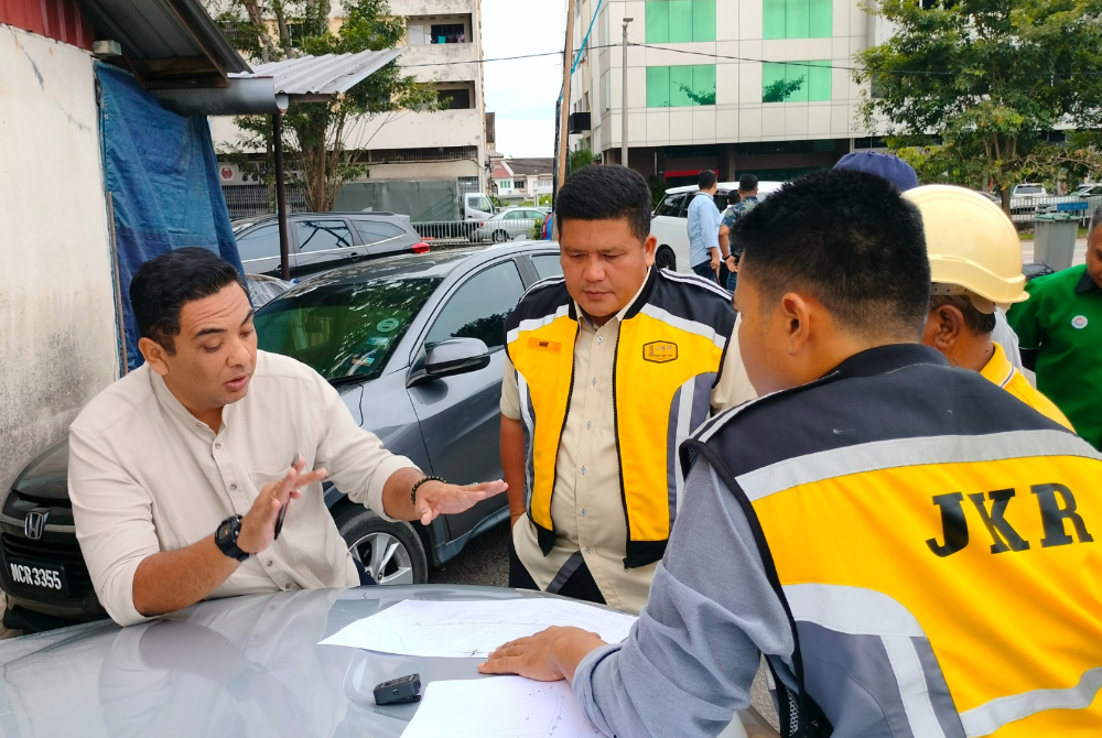 Mohd Noor Helmy (kiri) ketika berbincang dengan kakitangan JKR bagi mengatasi masalah banjir di Kampung Padang Semabok pada Isnin.