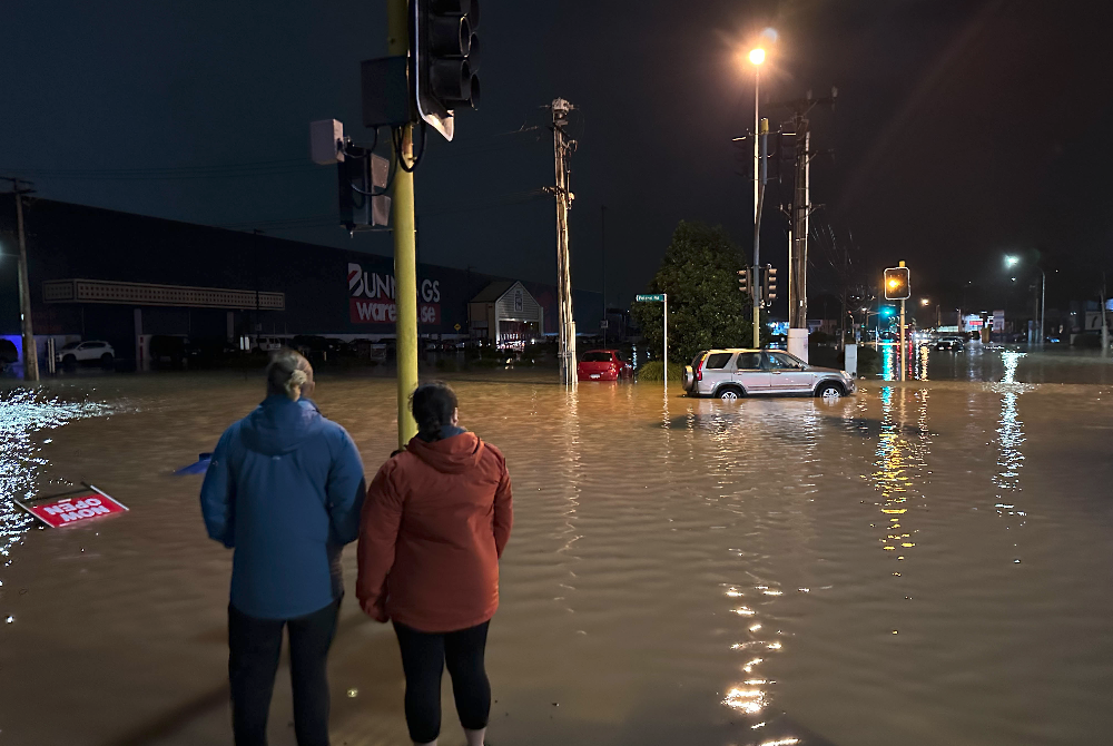 Orang ramai melihat jalan dinaiki air di Auckland, New Zealand pada Jumaat. - Foto Xinhua