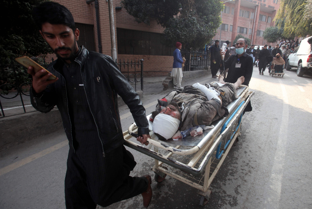 Orang ramai menolak pengusung yang membawa mangsa cedera selepas letupan masjid di dalam ibu pejabat polis, di sebuah hospital di Peshawar pada Isnin.