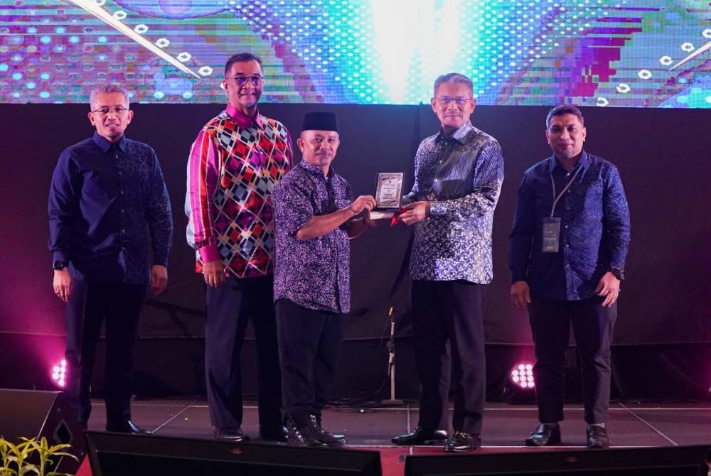 Wan Adnan (dua dari kanan) menyampaikan anugerah kepada seorang kakitangan Kumpulan PMINT.