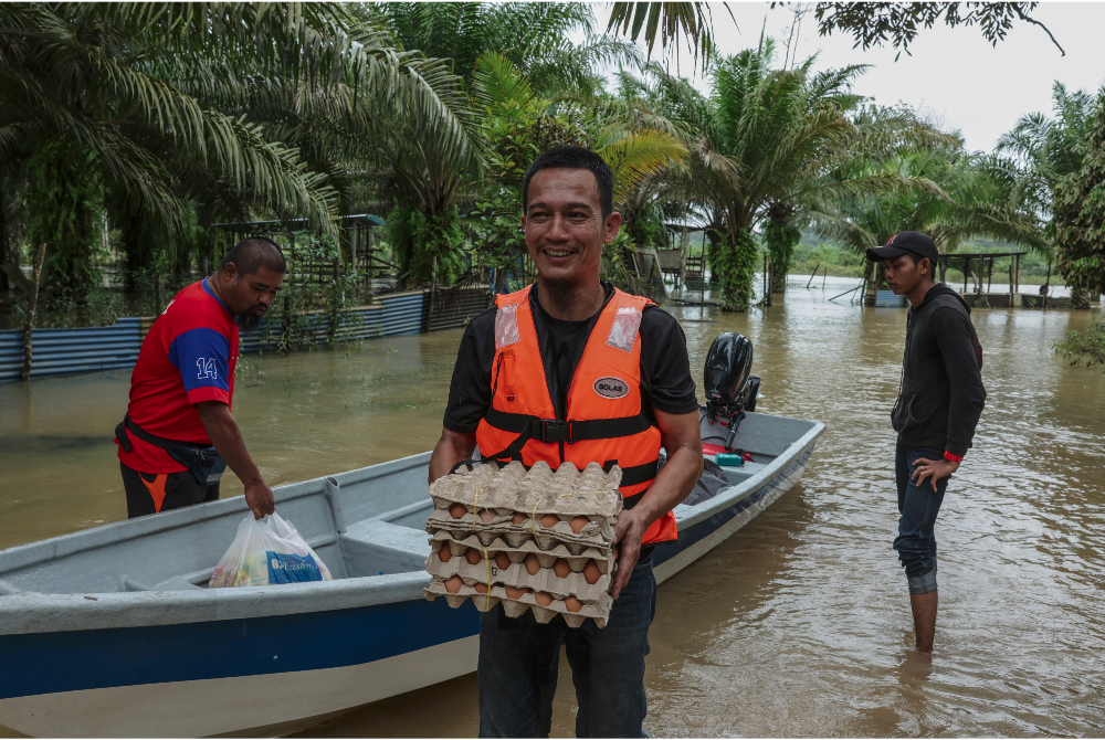 Penduduk Kampung Jamari, Mersing, Johor menaiki bot meredah sungai untuk menghantar bekalan makanan kepada sebahagian penduduk terkandas semula di kampung tersebut pada Ahad. - Foto Bernama
