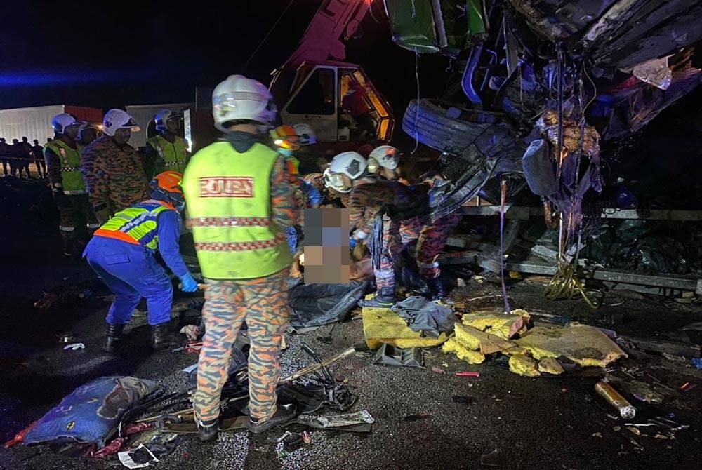 Anggota BBP Slim River membantu mengeluarkan mangsa yang maut dalam kejadian kemalangan membabitkan sebuah treler di KM371.7 Lebuhraya Utara Selatan arah selatan pada malam Rabu. - Foto JPBM Perak