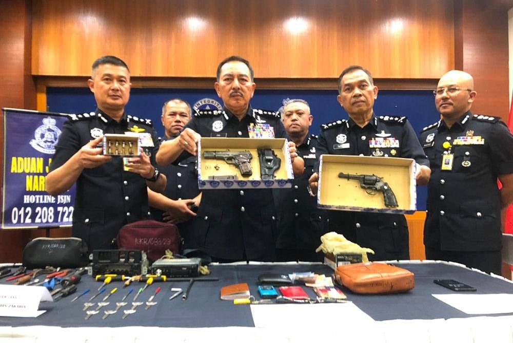 Muhamad Zaki (dua dari kiri) menunjukkan kedua-dua pistol dan peluru yang dirampas daripada dua suspek dalam kes berasingan dirampas ketika sidang akhbar pada Rabu.