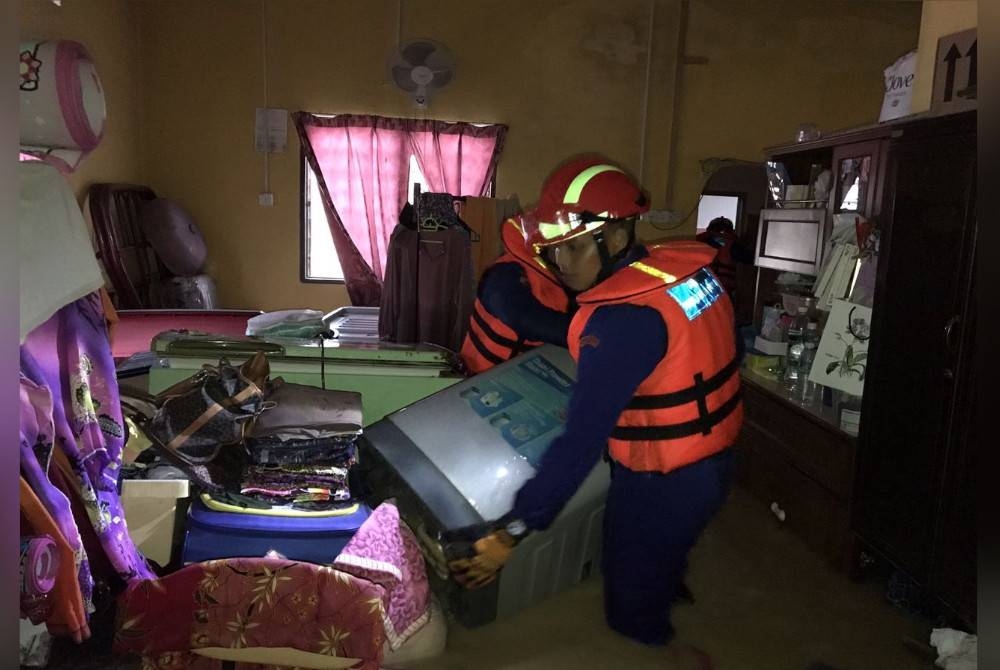 Vendredi, les membres de l'APM ont déplacé des objets vers un endroit sûr dans une maison inondée à Bandar Baharu.  - Photo de APM Bandar Haru