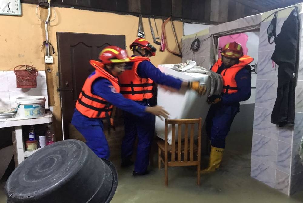 Vendredi, des membres de l'APM ont aidé à transporter des appareils électriques en lieu sûr dans une maison inondée à Bandar Baharu.  - Photo de APM Bandar Haru