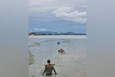 Anggota bomba menggunakan tali yang diikat pada badan berjaya menarik wanita itu ke darat. Foto JBPM